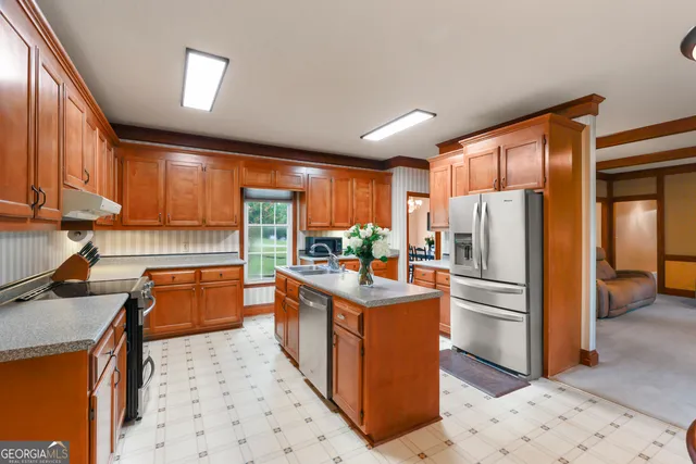 a kitchen with stainless steel appliances granite countertop a refrigerator a sink dishwasher a stove with wooden cabinets and floor