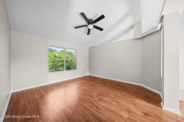 a view of empty room with wooden floor and ceiling fan