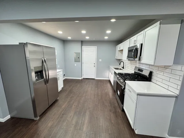 a kitchen with sink a refrigerator and wooden floor