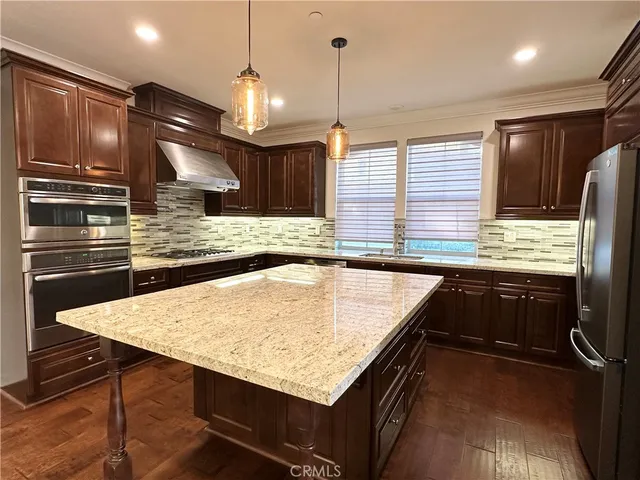 a kitchen with kitchen island granite countertop wooden cabinets a refrigerator and a sink