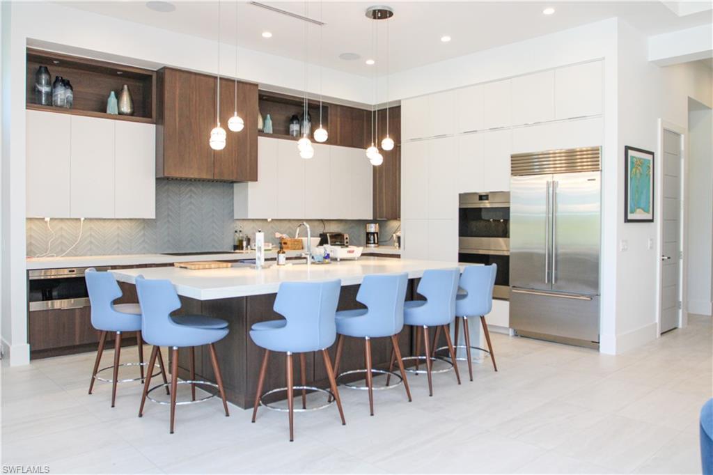 3123 Crayton Road Naples, FL 34103 - Photo 16 of 50 a kitchen with a dining table chairs refrigerator and stove