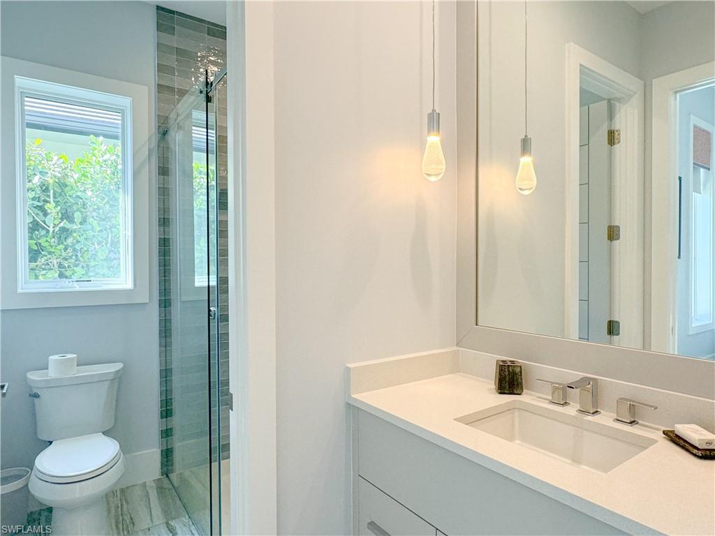 3123 Crayton Road Naples, FL 34103 - Photo 44 of 50 a bathroom with a granite countertop sink a toilet and a mirror