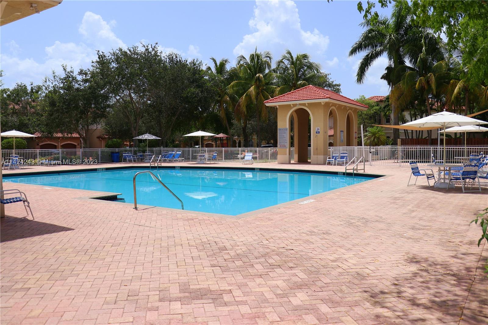 4929 Southwest 140th Terrace, Unit 5 Miramar, FL 33027 - Photo 24 of 24 a view of a swimming pool with lawn chairs under an umbrella