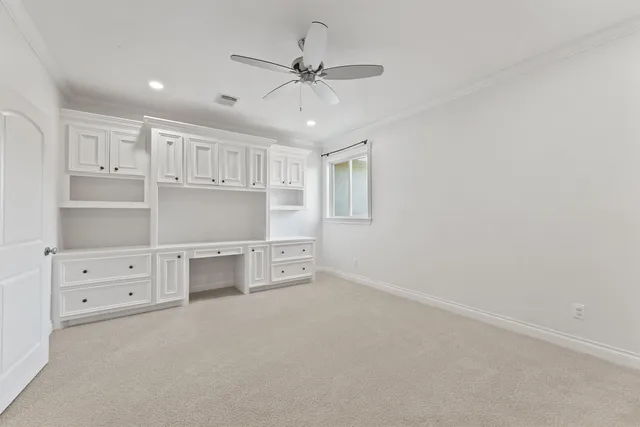 a view of an empty room with cabinet and a ceiling fan