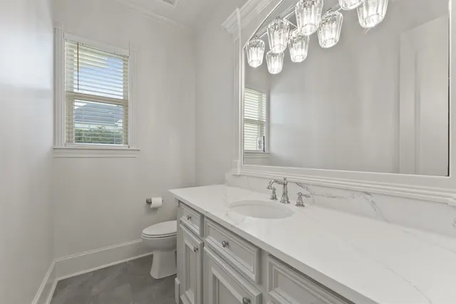 a bathroom with a granite countertop sink a toilet and a window