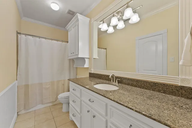 a bathroom with a granite countertop sink a toilet and a mirror