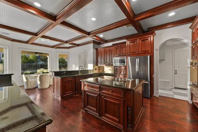 a kitchen with stainless steel appliances granite countertop a stove a refrigerator a sink and white cabinets with wooden floor