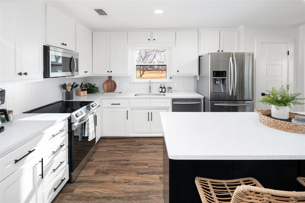 1169 Willow Road Graford, TX 76449 - Photo 9 of 40 a kitchen with white cabinets and stainless steel appliances