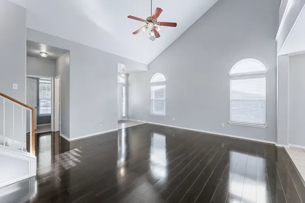 a view of an empty room with wooden floor and a window