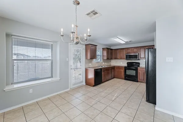 a kitchen with stainless steel appliances kitchen island granite countertop a refrigerator a sink dishwasher and a stove with wooden floor