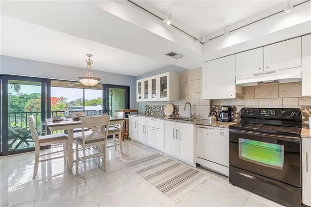 a kitchen with stainless steel appliances granite countertop a stove a sink dishwasher a dining table and chairs with wooden floor