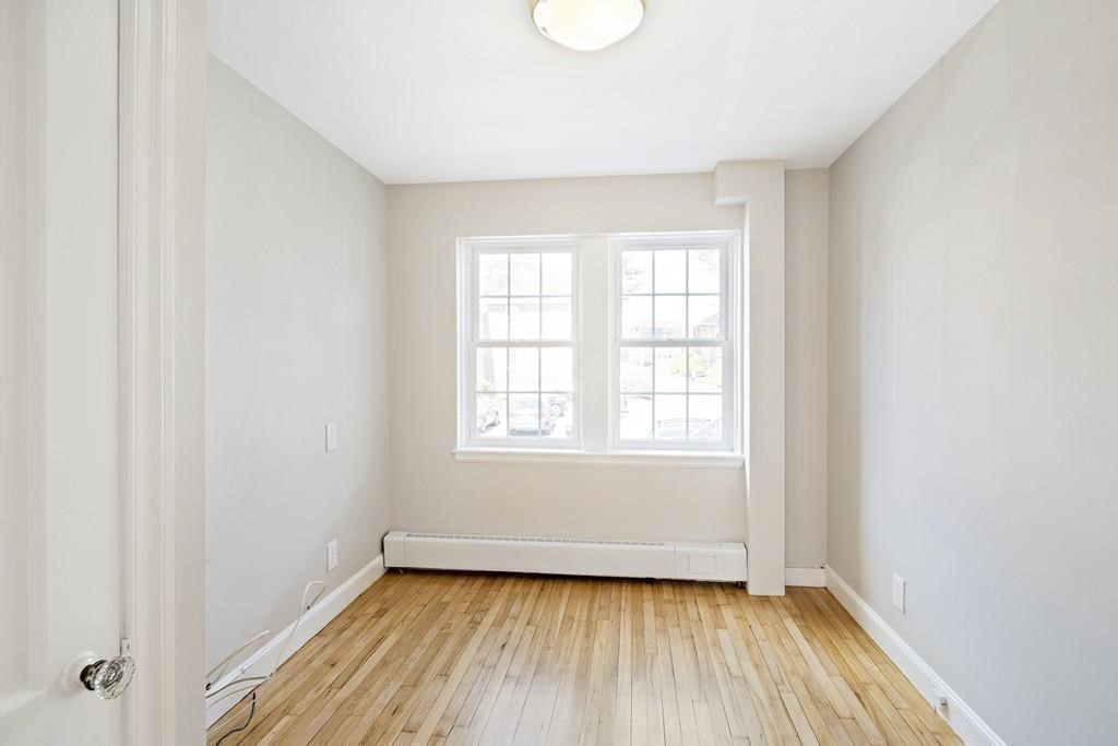 23 Hammond Pond Parkway, Unit 2 Newton, MA 02467 - Photo 16 of 21 an empty room with wooden floor and windows