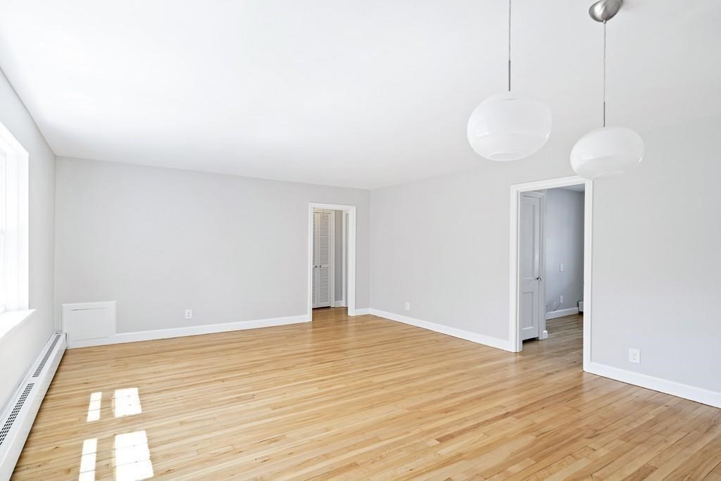23 Hammond Pond Parkway, Unit 2 Newton, MA 02467 - Photo 8 of 21 a view of an empty room with wooden floor and a window