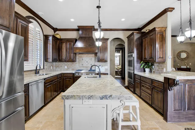 a kitchen with stainless steel appliances granite countertop a sink a stove and a refrigerator