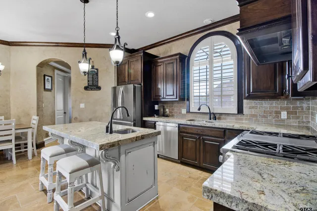 a kitchen with stainless steel appliances granite countertop a sink a stove and a wooden floors