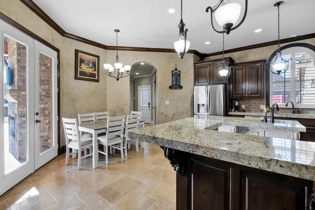 a kitchen with granite countertop a table chairs and a chandelier