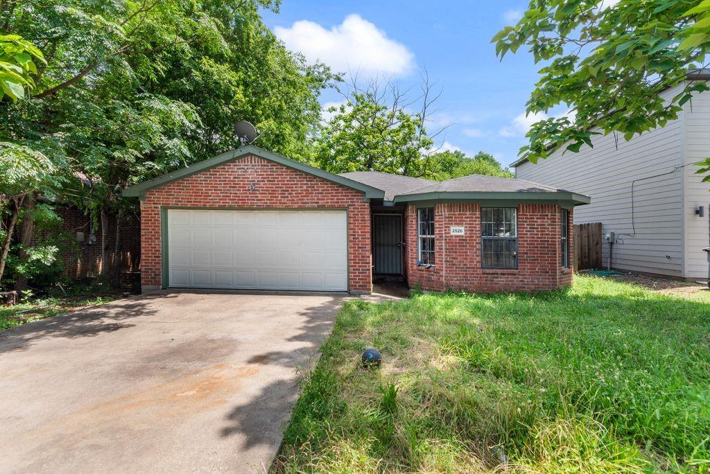 2526 Exeter Avenue Dallas, TX 75216 - Photo 5 of 19 Brick exterior featuring an attached garage with a white door, a paved driveway, and mature perimeter trees