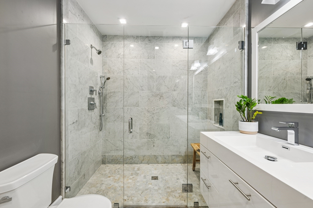 27 Mercer Street, Unit 1 Boston, MA 02127 - Photo 16 of 21 a bathroom with a shower sink vanity mirror and toilet