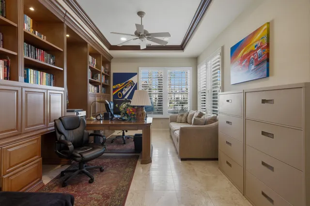 a living room with furniture a chandelier fan and a large window
