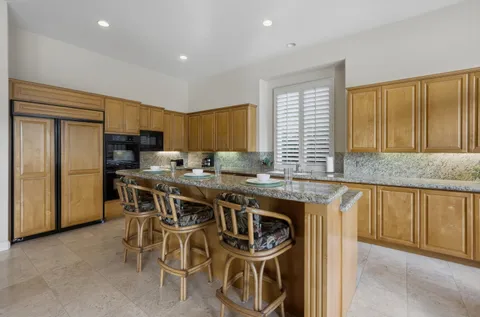 a kitchen with stainless steel appliances granite countertop a table chairs sink refrigerator and cabinets