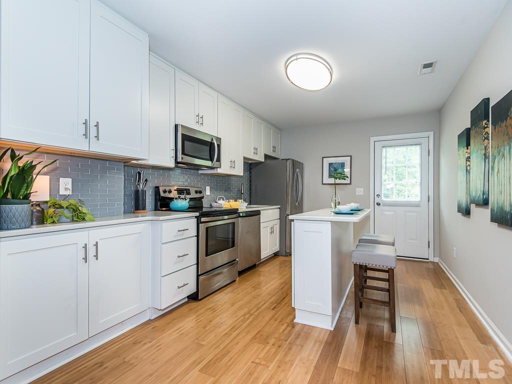 1312 South State Street, Unit D Raleigh, NC 27610 - Photo 7 of 19 a kitchen with a refrigerator a stove top oven a sink dishwasher and white cabinets with wooden floor