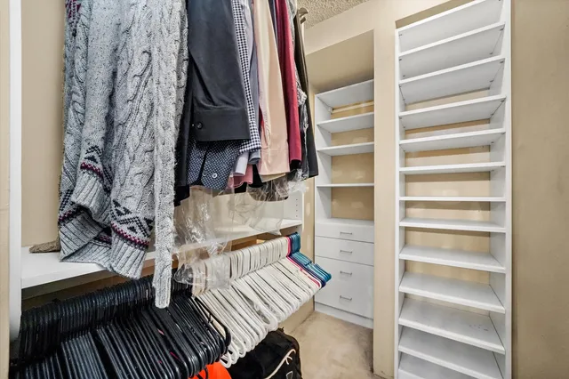 a view of walk in closet with clothes and shoes
