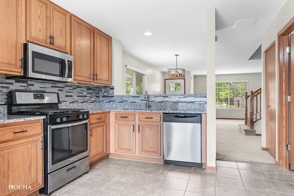2413 Roxbury Lane Montgomery, IL 60538 - Photo 6 of 22 a kitchen with stainless steel appliances granite countertop a stove microwave and sink