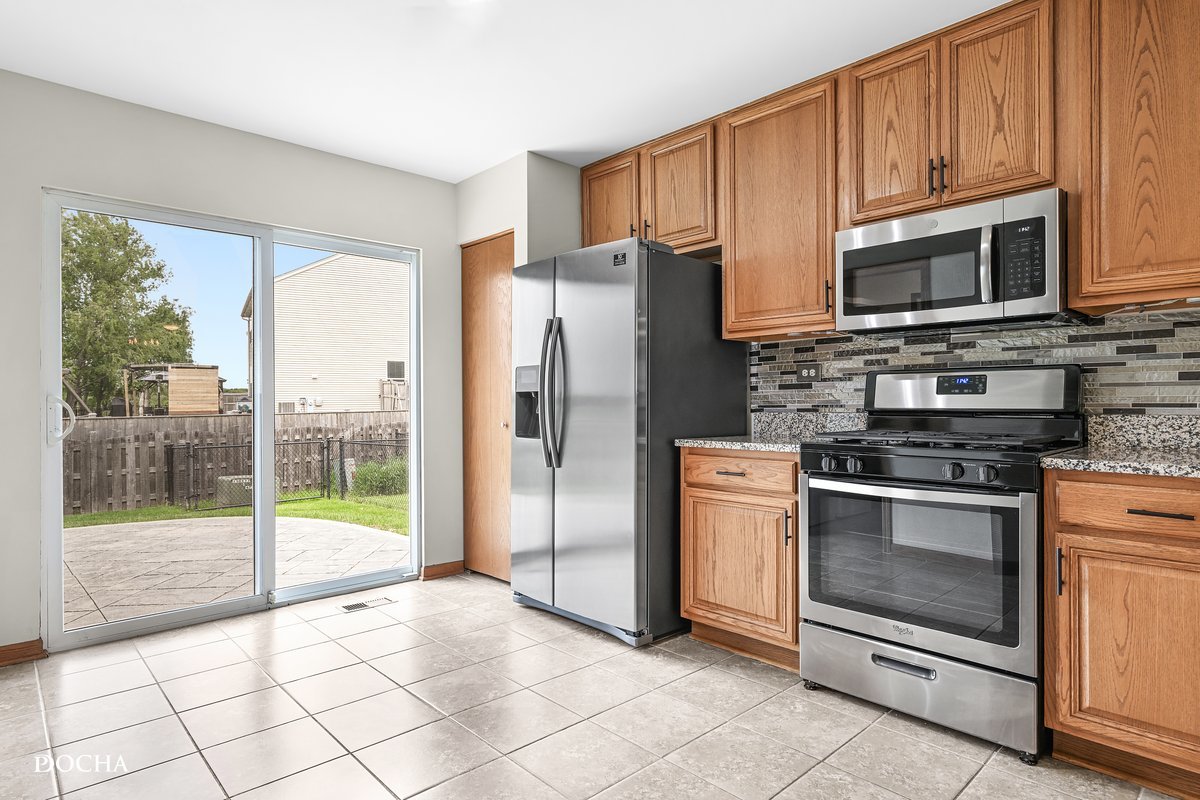 2413 Roxbury Lane Montgomery, IL 60538 - Photo 7 of 22 a kitchen with granite countertop a refrigerator and a stove top oven