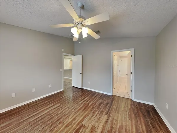 an empty room with wooden floor fan and windows