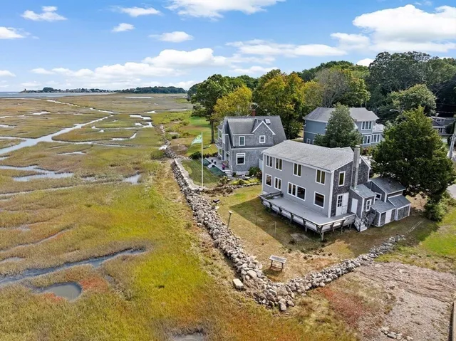 a view of a swimming pool with lawn chairs and large trees