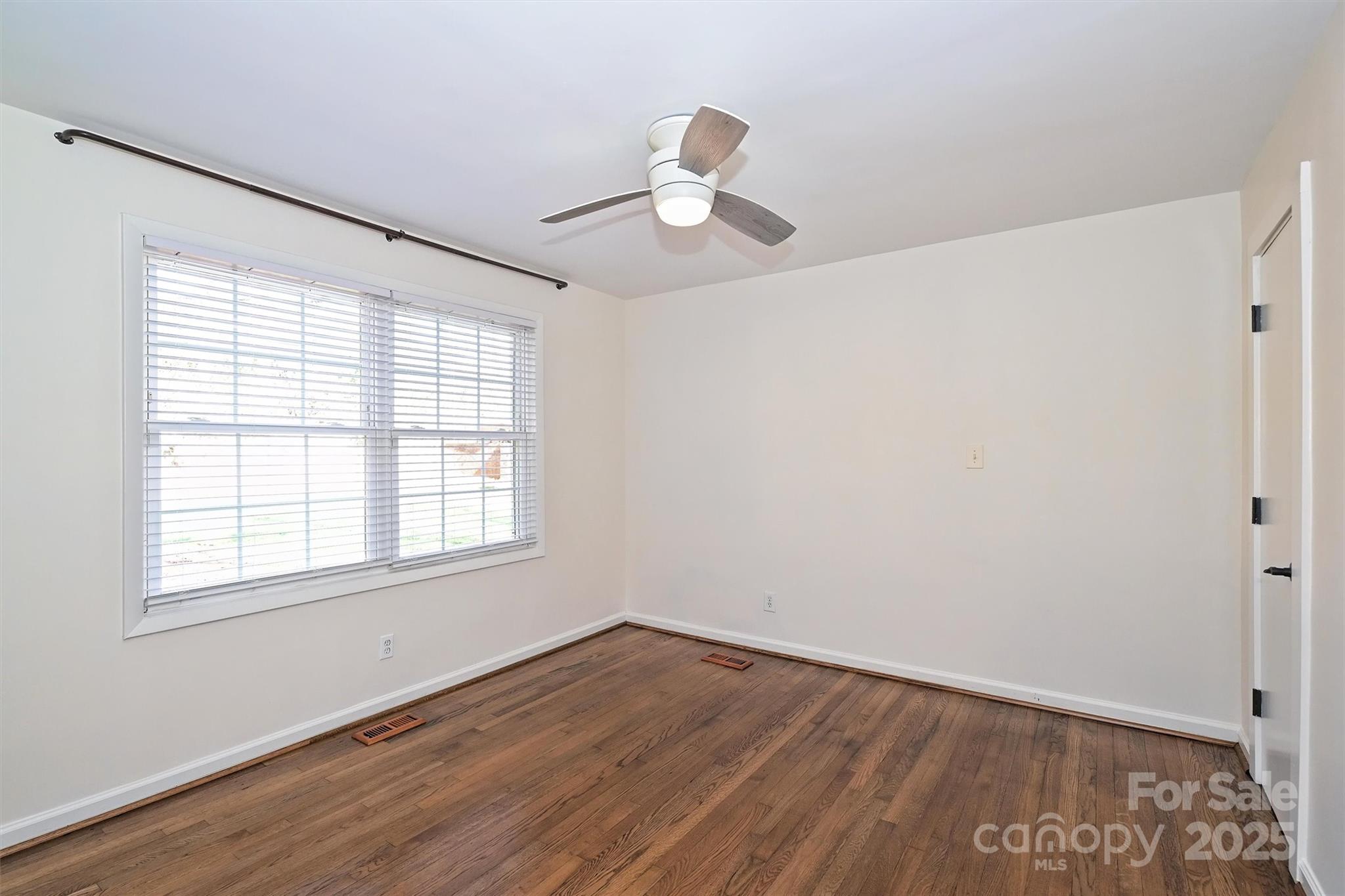 2730 Royston Road Charlotte, NC 28208 - Photo 25 of 40 an empty room with wooden floor chandelier fan and windows
