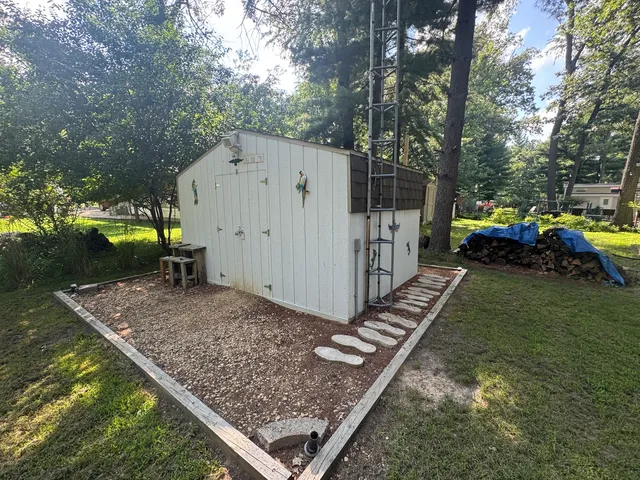 a view of a backyard with large trees and wooden fence
