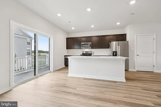a view of kitchen with stainless steel appliances wooden floor large window and wooden floor