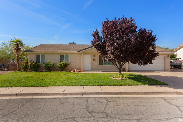 664 East Springhill Drive Washington, UT 84780 - Photo 3 of 21 Single-story residence featuring a neutral-toned exterior, an attached two-car garage, and a manicured front lawn