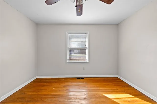 a view of empty room with window and wooden floor