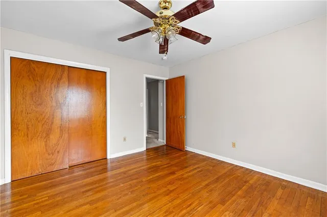 an empty room with wooden floor closet and windows