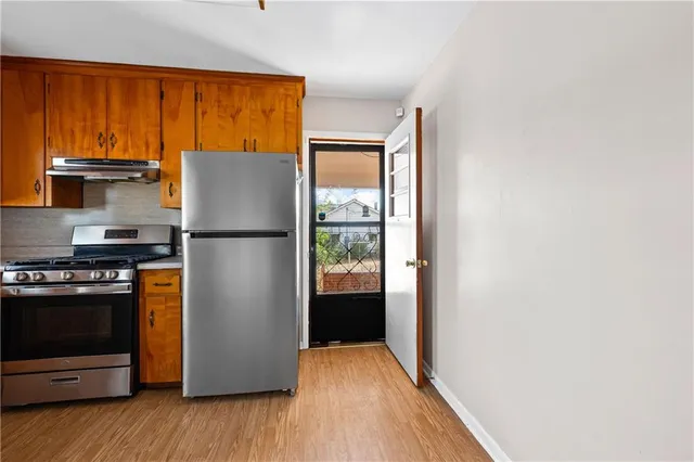 a kitchen with kitchen island wooden floor and stainless steel appliances
