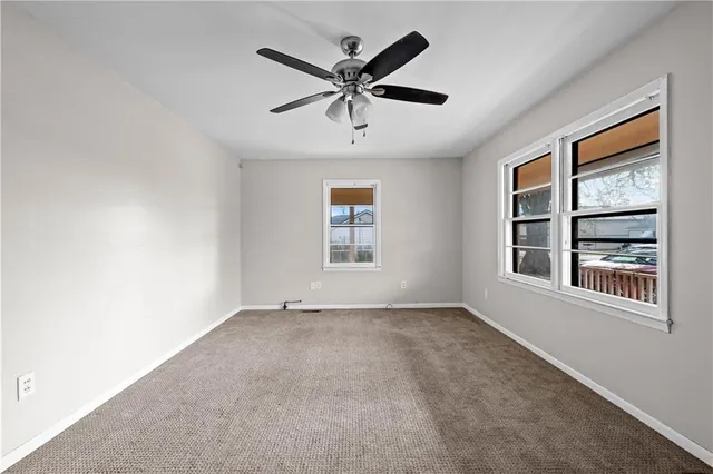 an empty room with windows and ceiling fan