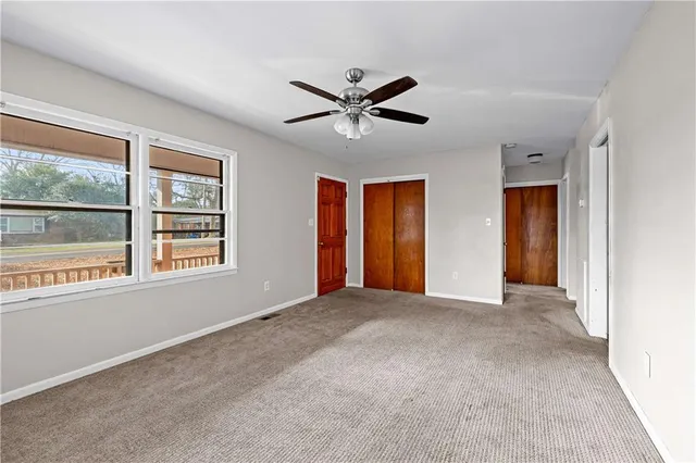 a view of an empty room with window and ceiling fan