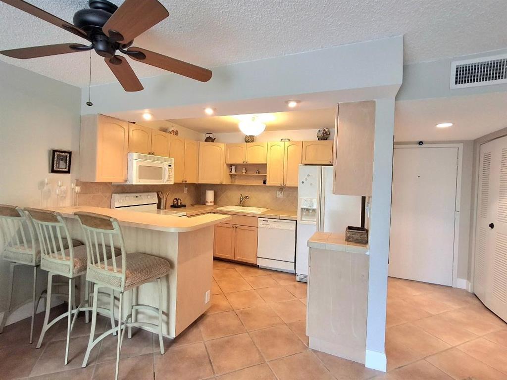 1421 South Ocean Boulevard, Unit 206 Pompano Beach, FL 33062 - Photo 11 of 40 a kitchen with a sink a counter top space appliances and cabinets