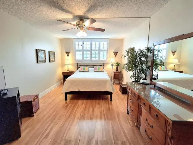 a spacious bedroom with a large bed a chandelier and windows