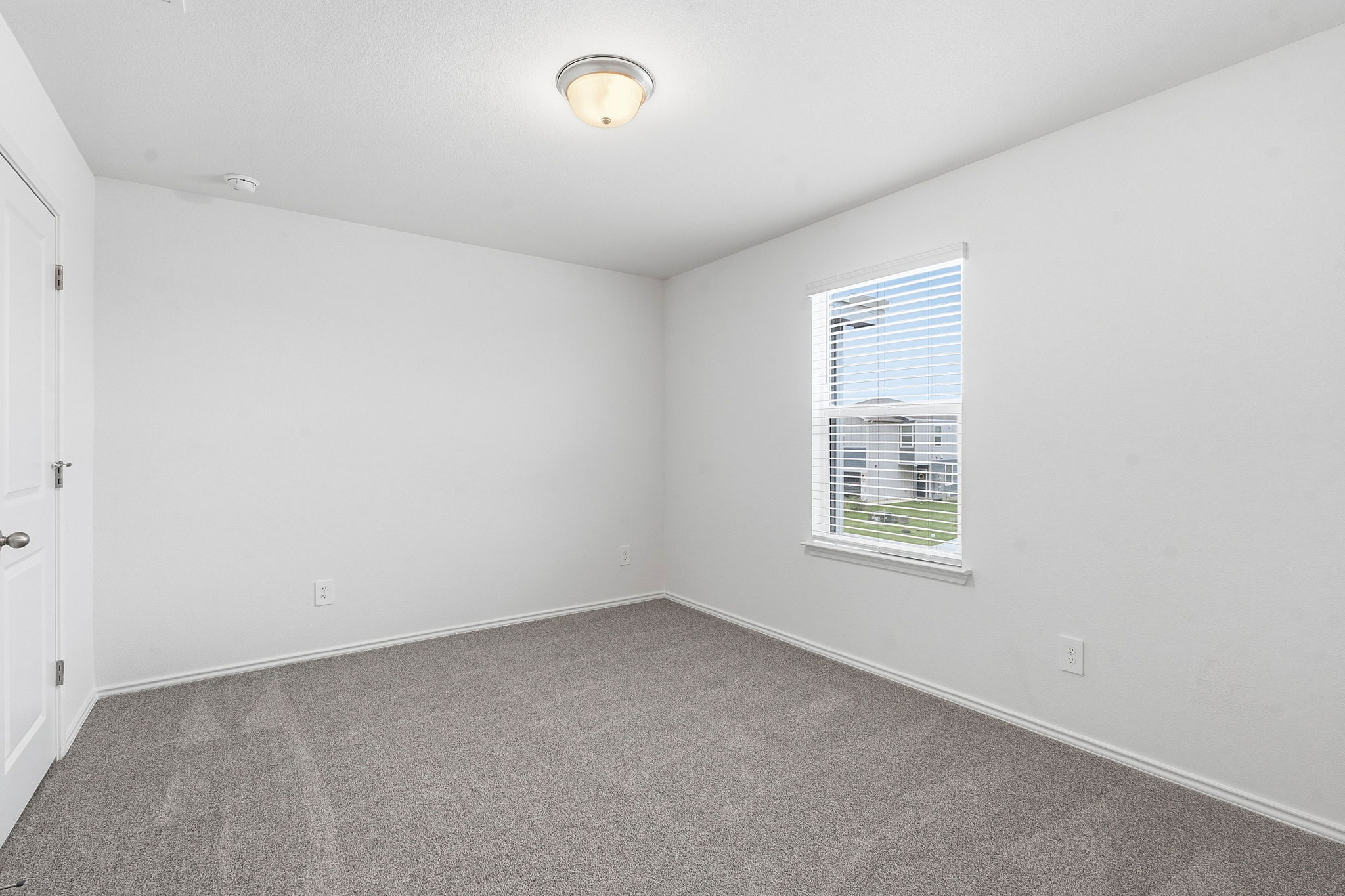 164 Cinnabar Lane, Unit 3 Kyle, TX 78640 - Photo 16 of 20 Carpeted room with a single window featuring white blinds, a white door with a round knob, and a ceiling-mounted light fixture