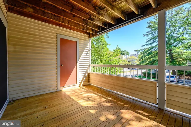 a view of an empty room with wooden floor and windows
