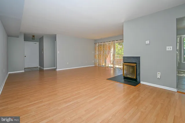 a view of empty room with wooden floor and fireplace