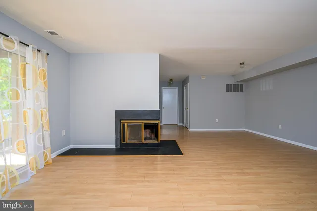 a view of an empty room with a fireplace and a window