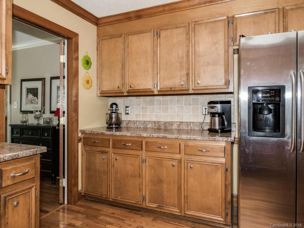 7301 Alexander Road Charlotte, NC 28270 - Photo 7 of 24 a kitchen with stainless steel appliances granite countertop a refrigerator a stove and a sink with wooden cabinets