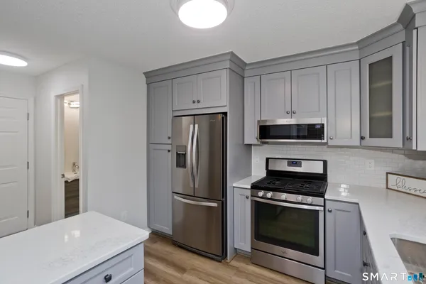 a kitchen with stainless steel appliances a refrigerator stove and white cabinets