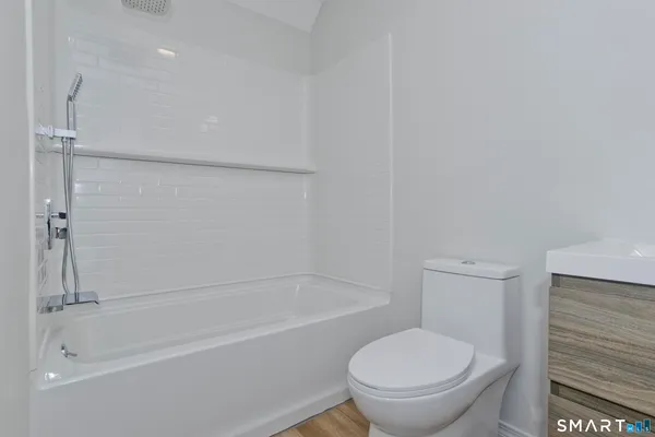 a white toilet sitting next to a bath tub