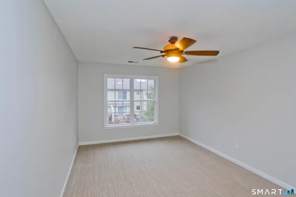 an empty room with windows and chandelier fan