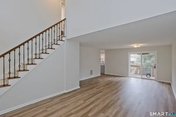 a view of an empty room with wooden floor and stairs
